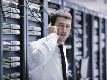 A man in a tie is talking on the phone in a server room.