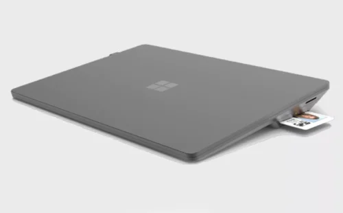 A microsoft surface laptop with an id card attached to it.