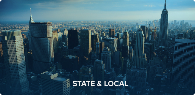 Aerial view of a city skyline featuring the Empire State Building, with "new state & local" text overlay at the bottom.