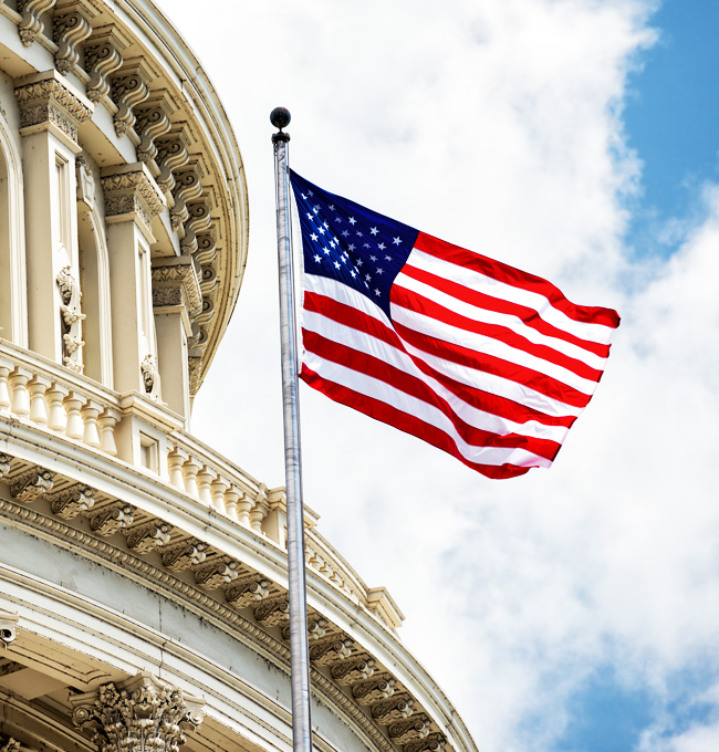An American flag waves in front of the United States Capitol building against a partly cloudy sky, embodying the spirit of Mission Planning as it stands guard over the heart of democracy.