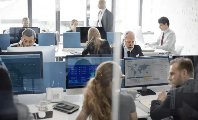 People working at Logicad workstations in a busy office environment with Ace computers displaying data, charts, and maps.